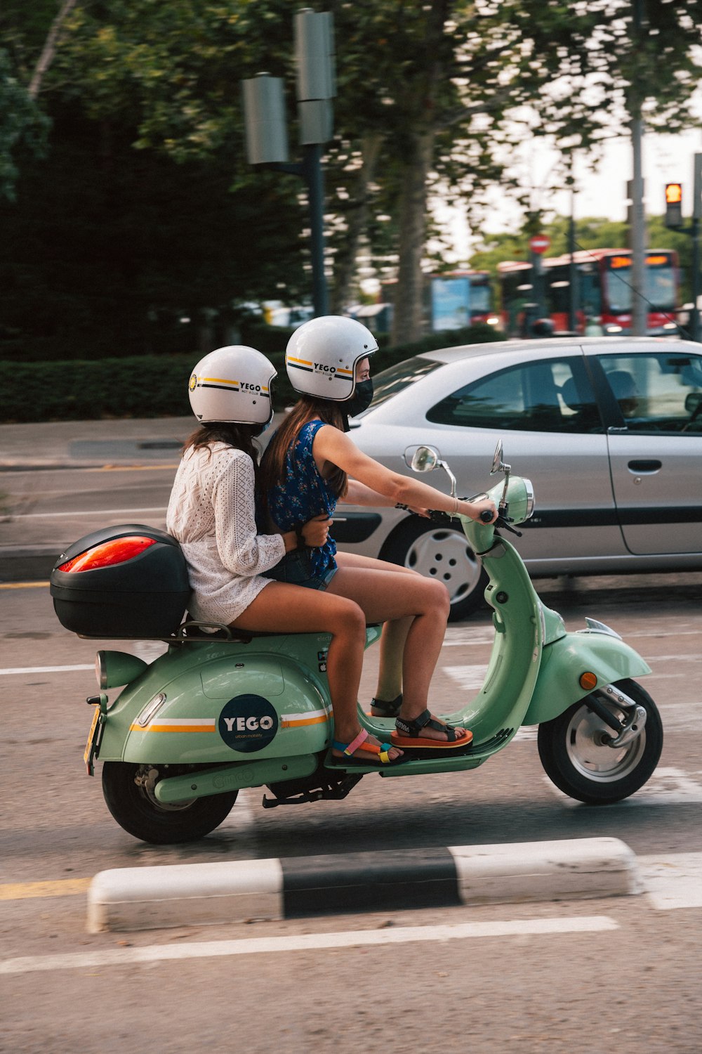 woman in blue denim shorts and white helmet riding green motor scooter during daytime