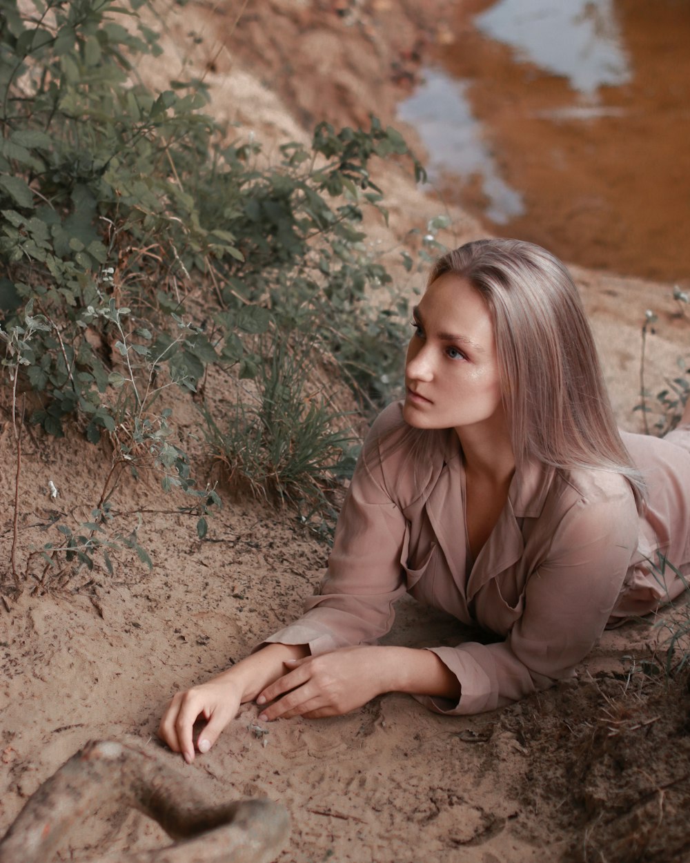 Femme en chemise à manches longues marron assise sur un sol brun pendant la journée