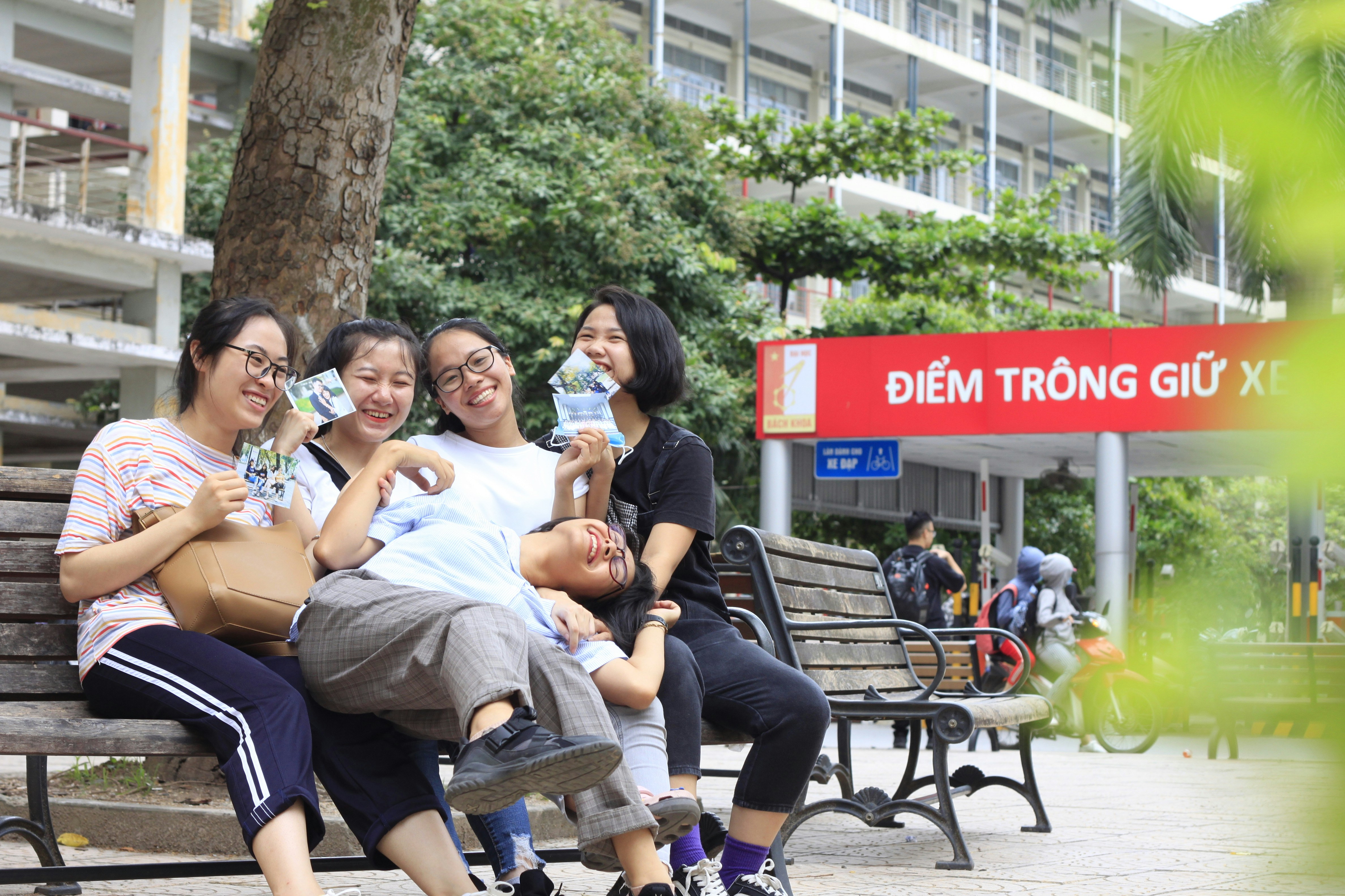 3 women sitting on brown wooden bench