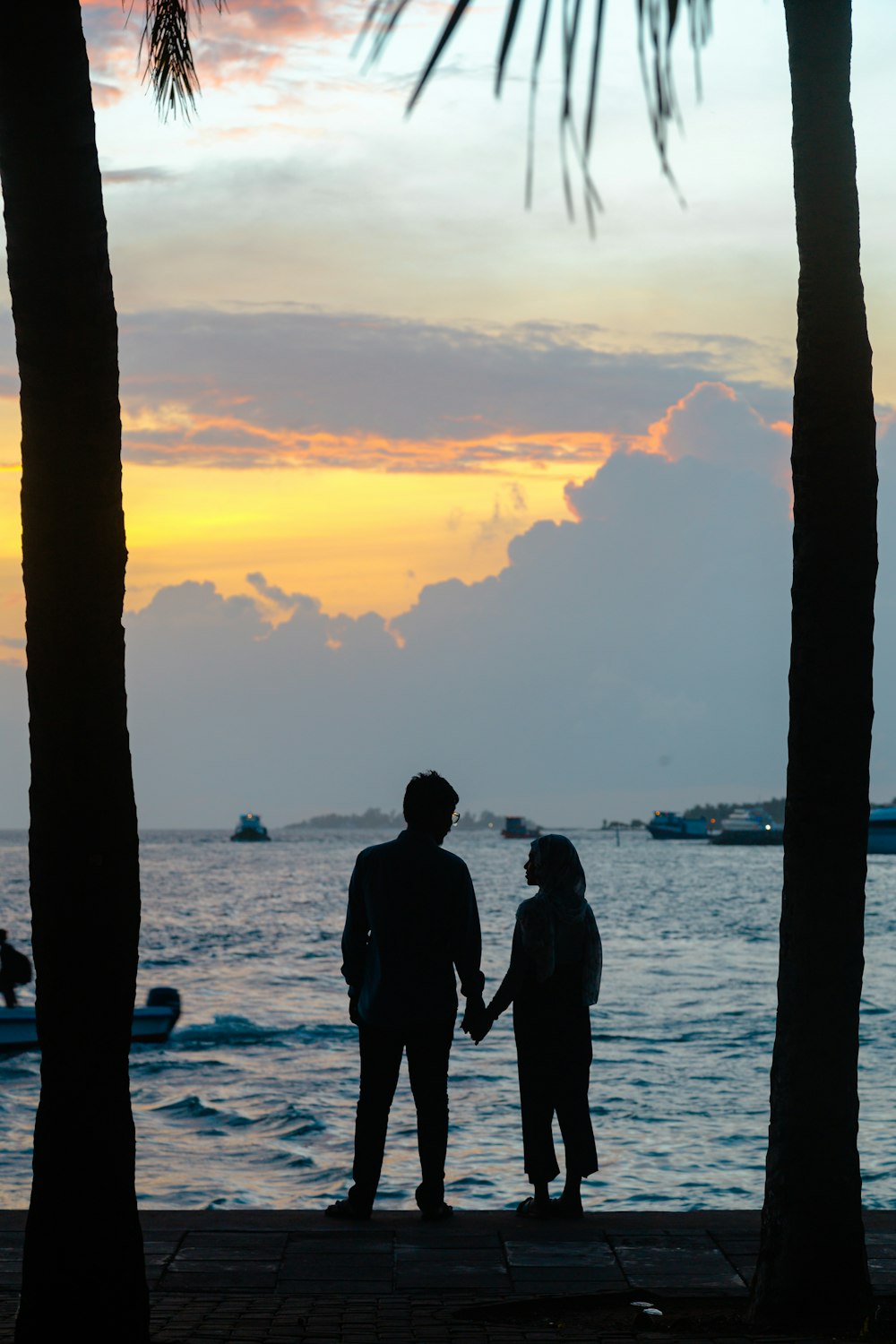 silhouette of 2 men standing on seashore during sunset
