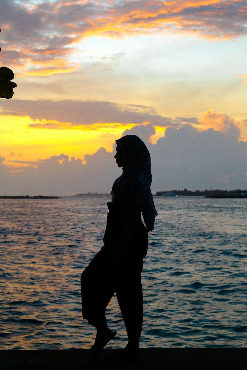 Silueta de mujer de pie en la orilla del mar durante la puesta del sol