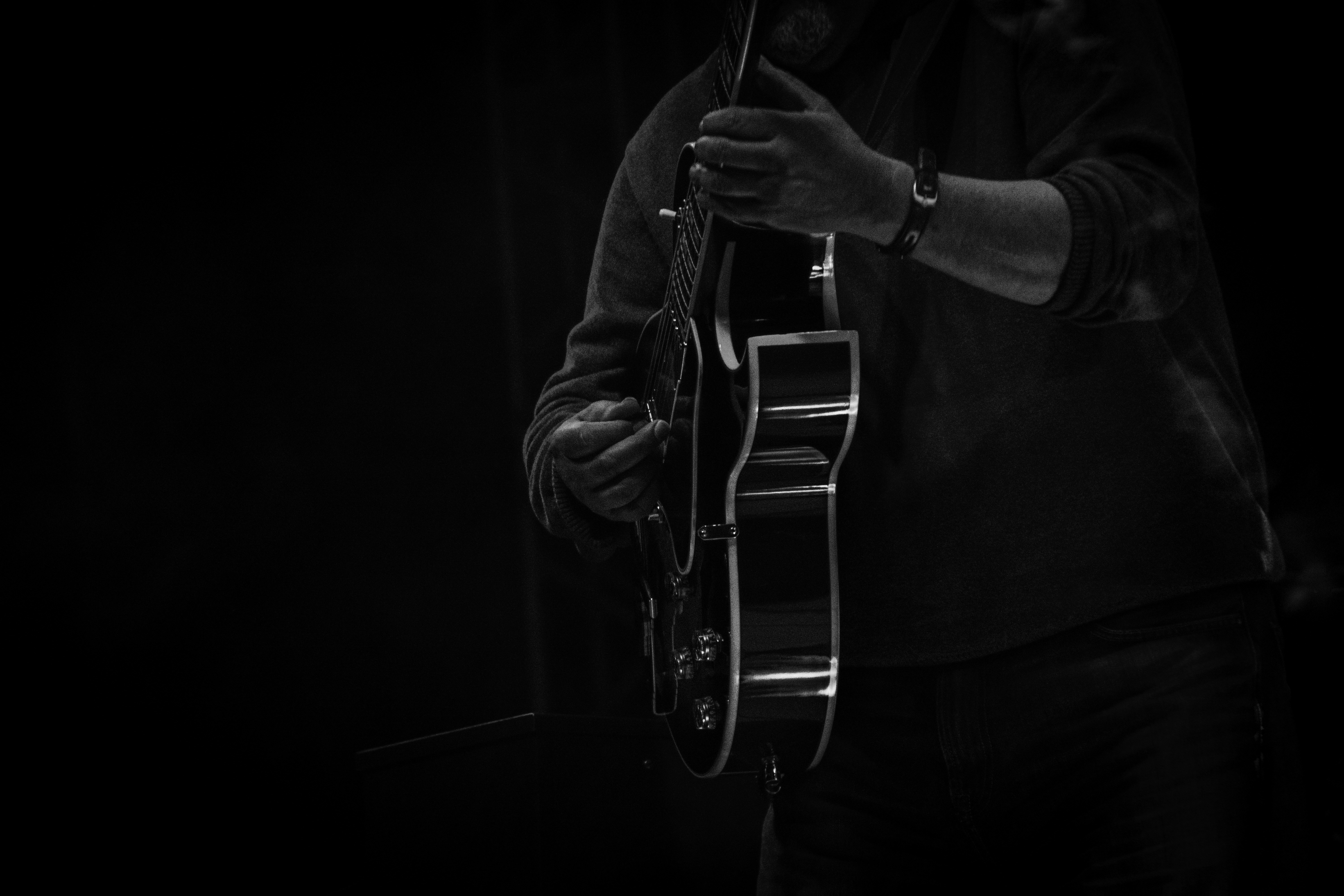 man playing guitar in grayscale photography