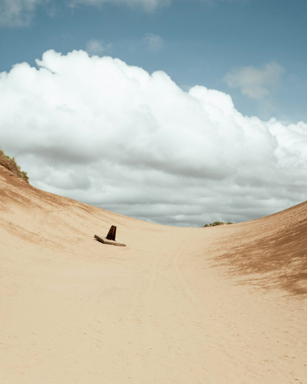 person walking on sand under white clouds during daytime