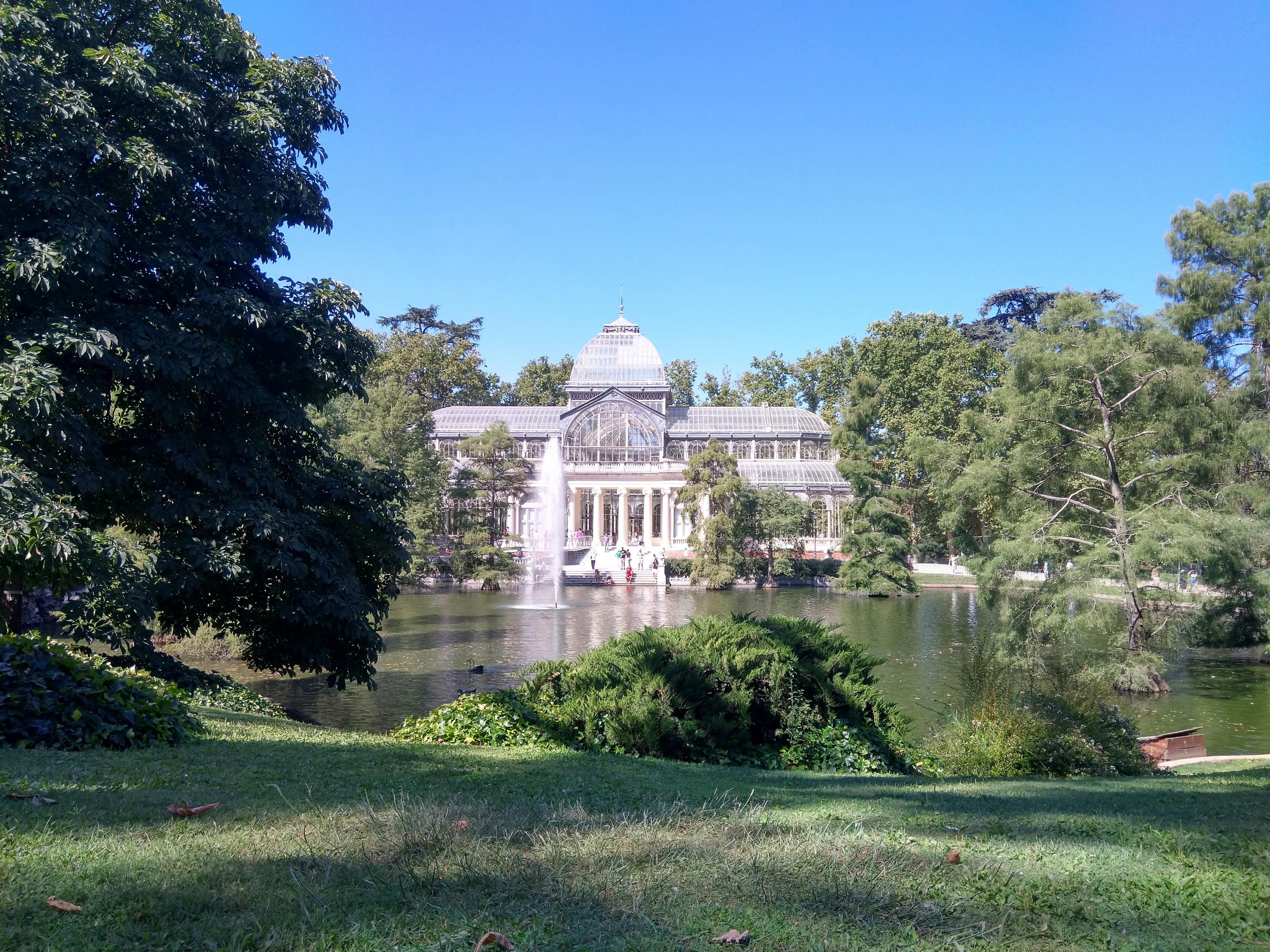 Bâtiment en béton blanc près des arbres verts et de la rivière pendant la journée