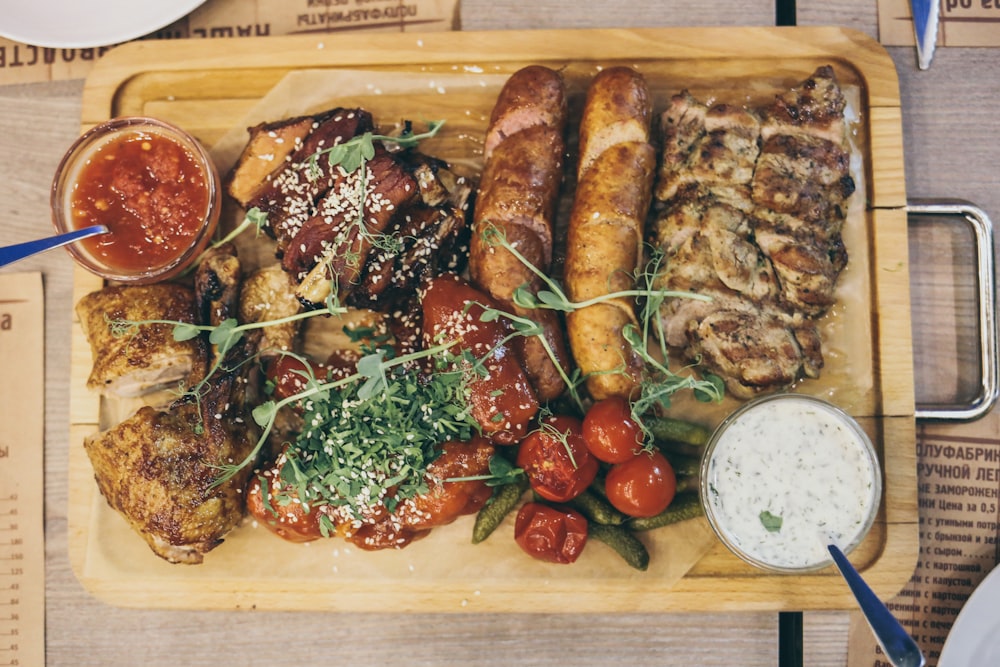 grilled meat with green vegetable and tomato on brown wooden tray