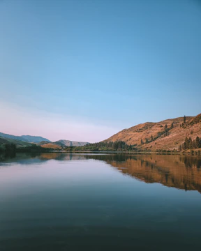 A flat, open plot near a calm lake reflecting the sky.