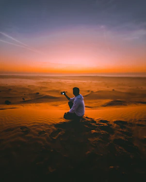A photographer capturing a sunset over the sand dunes of Merzouga desert.