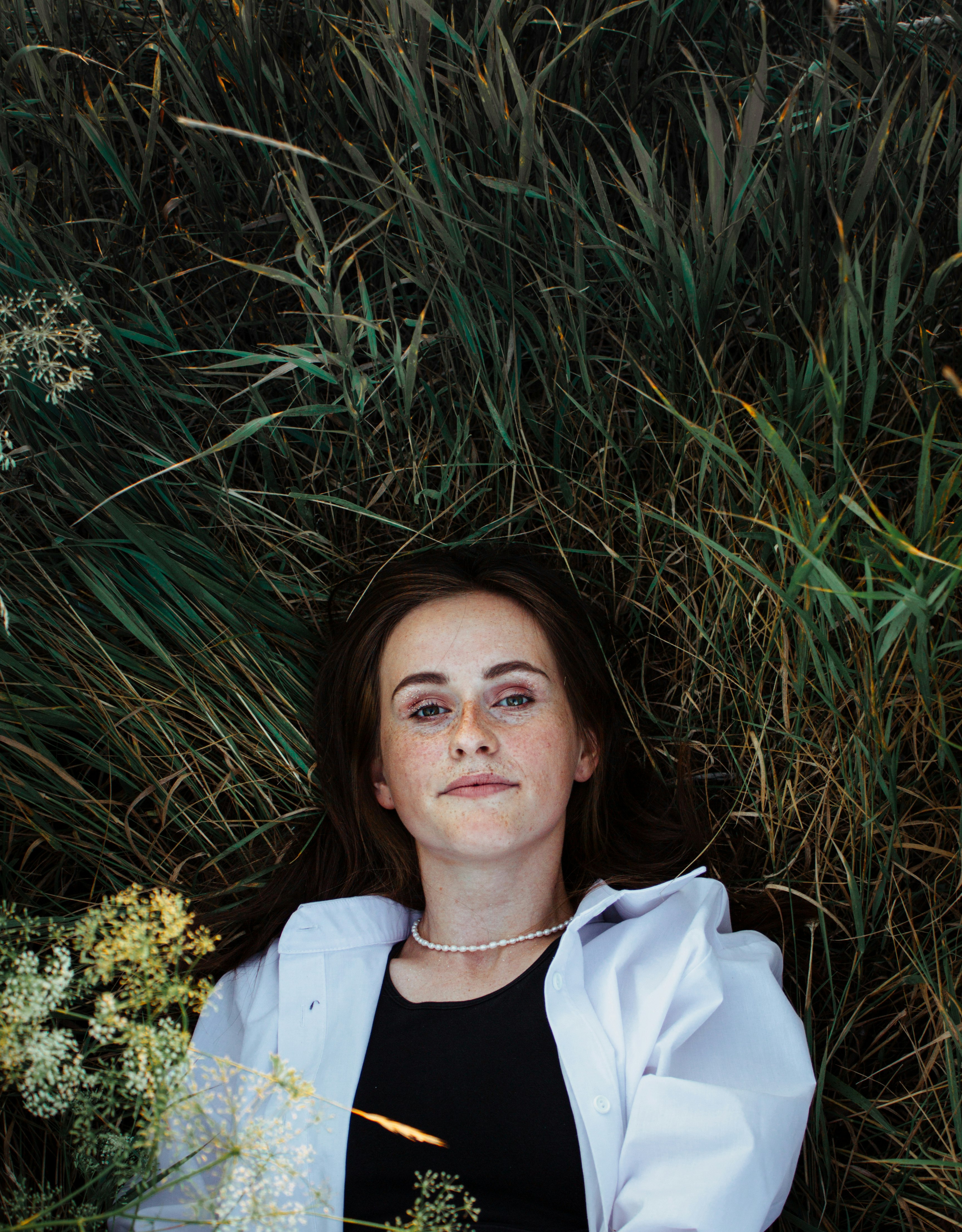 woman in white crew neck shirt lying on green grass during daytime