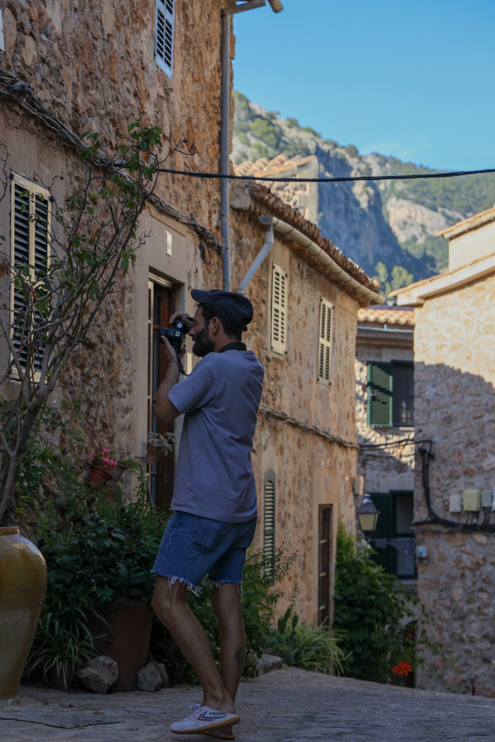 man in gray t-shirt and blue shorts holding black dslr camera