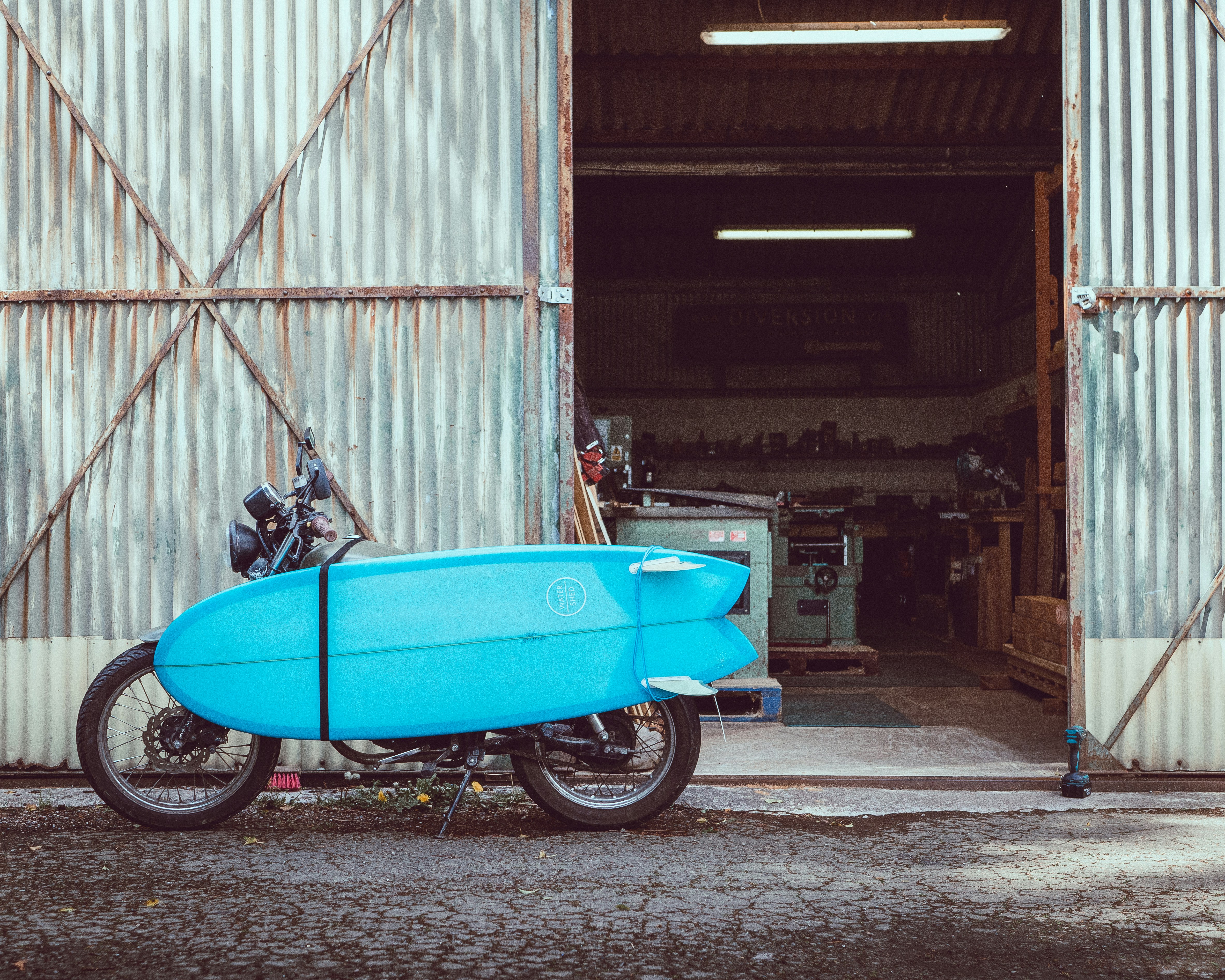 blue motor scooter parked beside white wall