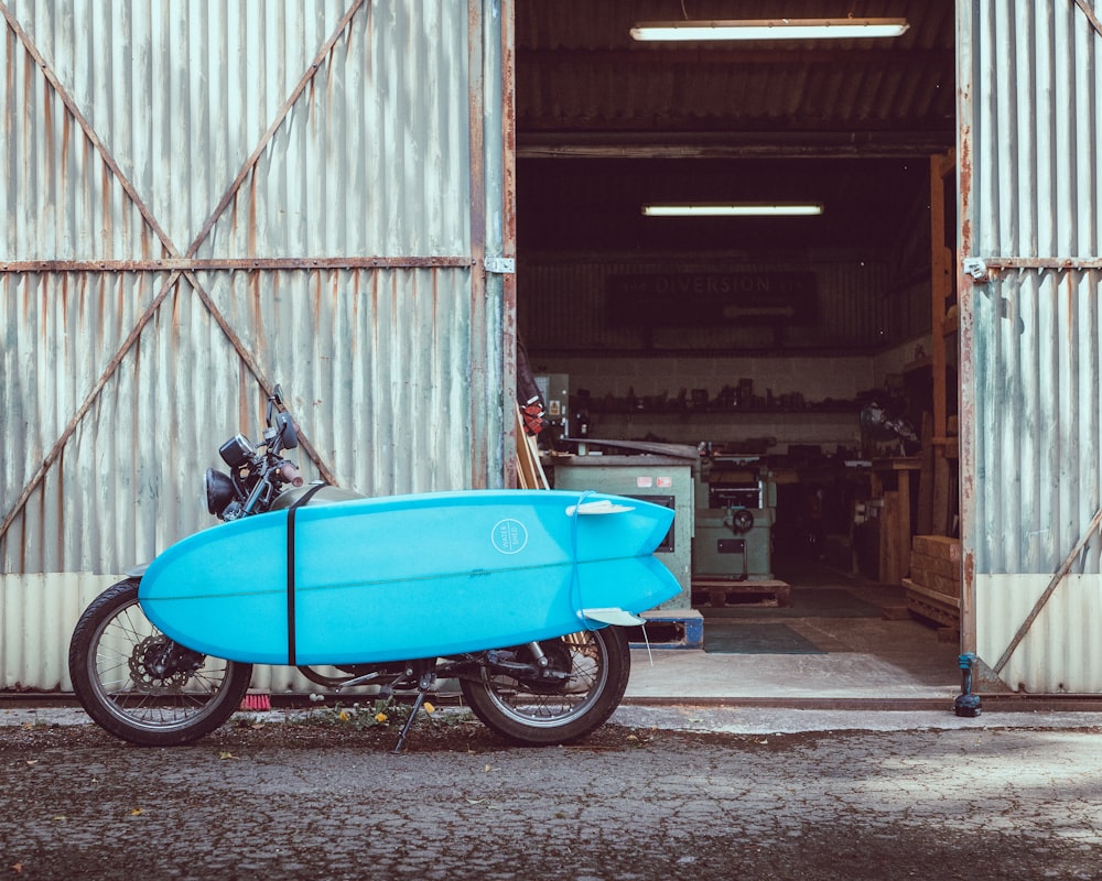 blue motor scooter parked beside white wall