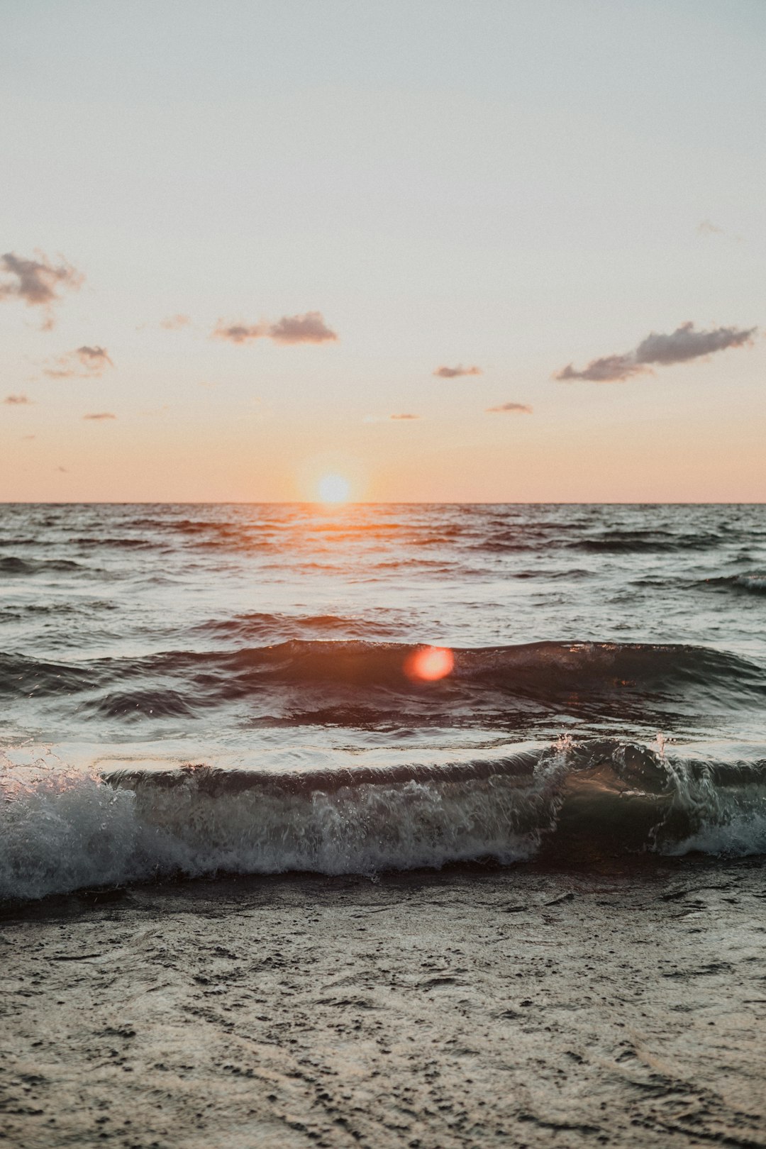 ocean waves crashing on shore during sunset