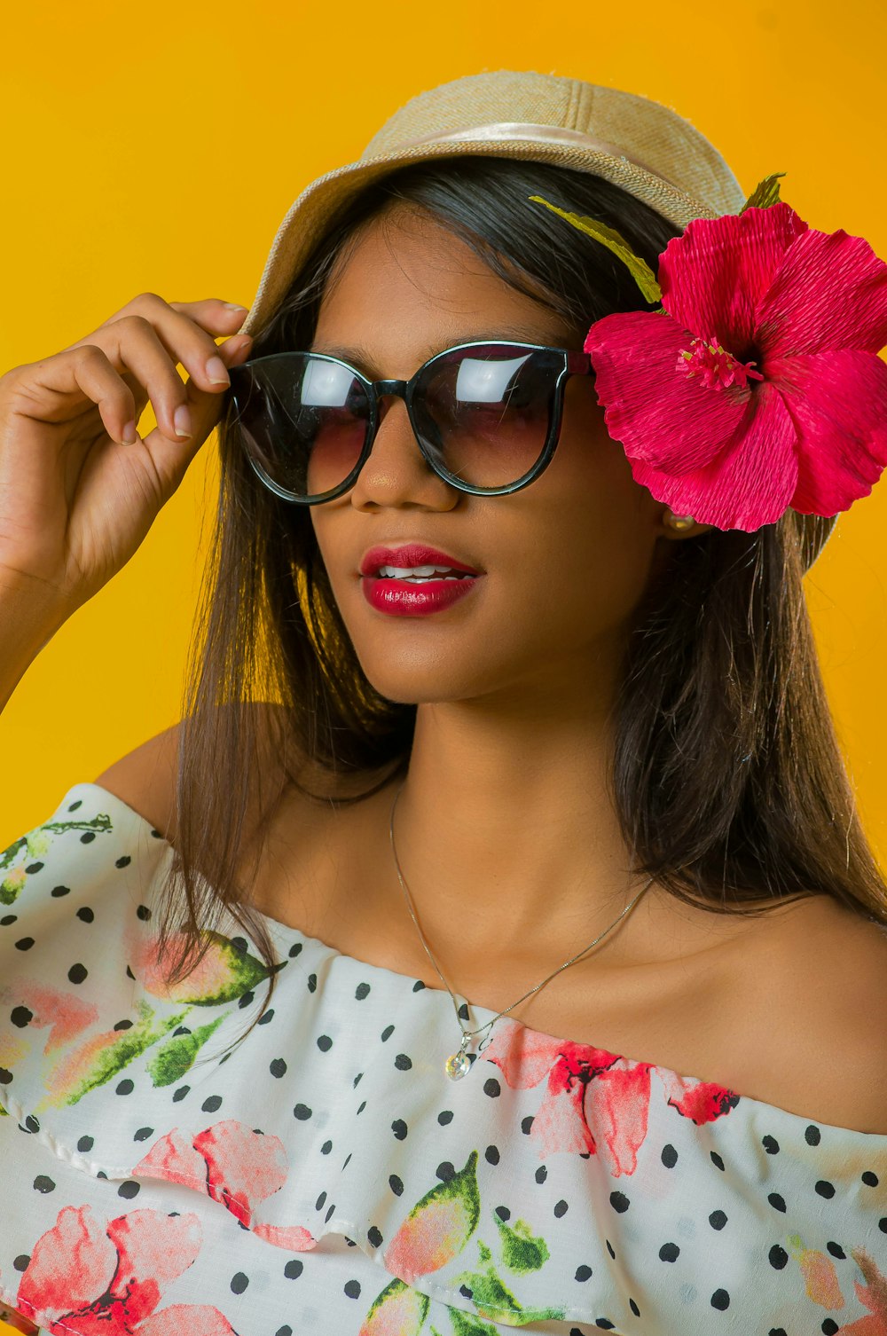 woman in white and red floral shirt wearing black sunglasses