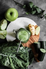 green apple beside stainless steel cup with green liquid