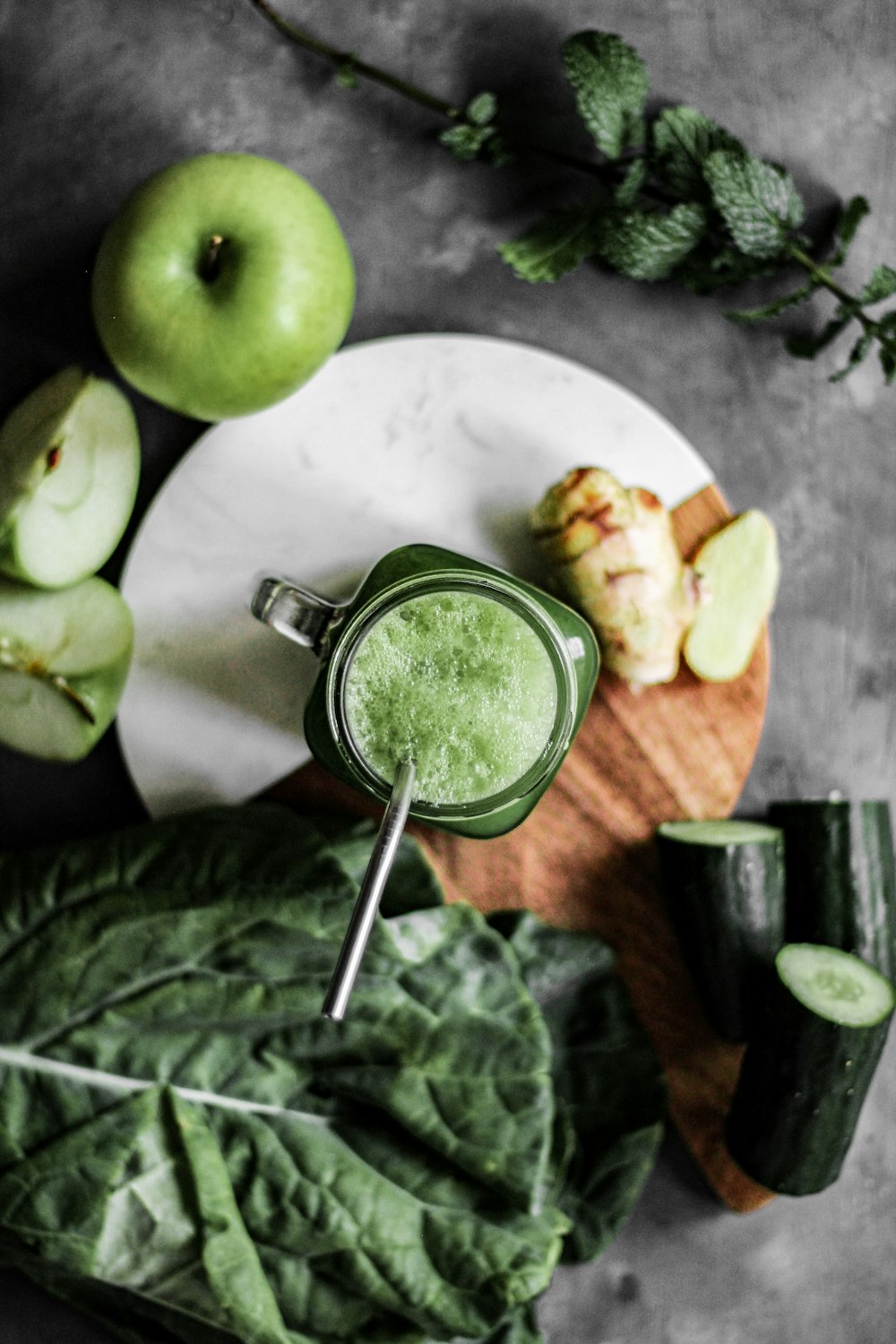 grüner Apfel neben Edelstahlbecher mit grüner Flüssigkeit