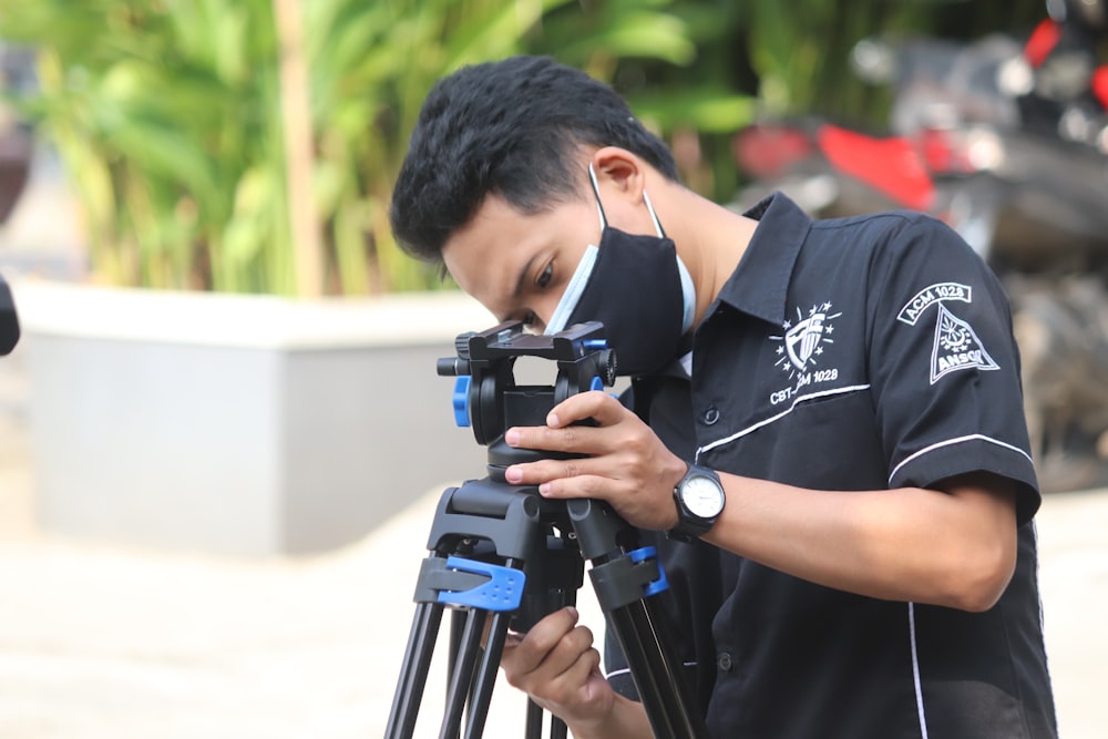 man in black and white crew neck t-shirt using black dslr camera during daytime