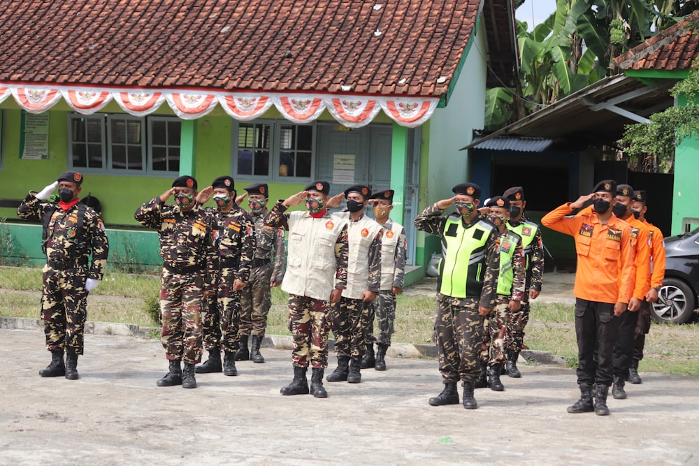 people in green and black camouflage uniform standing on gray concrete floor during daytime