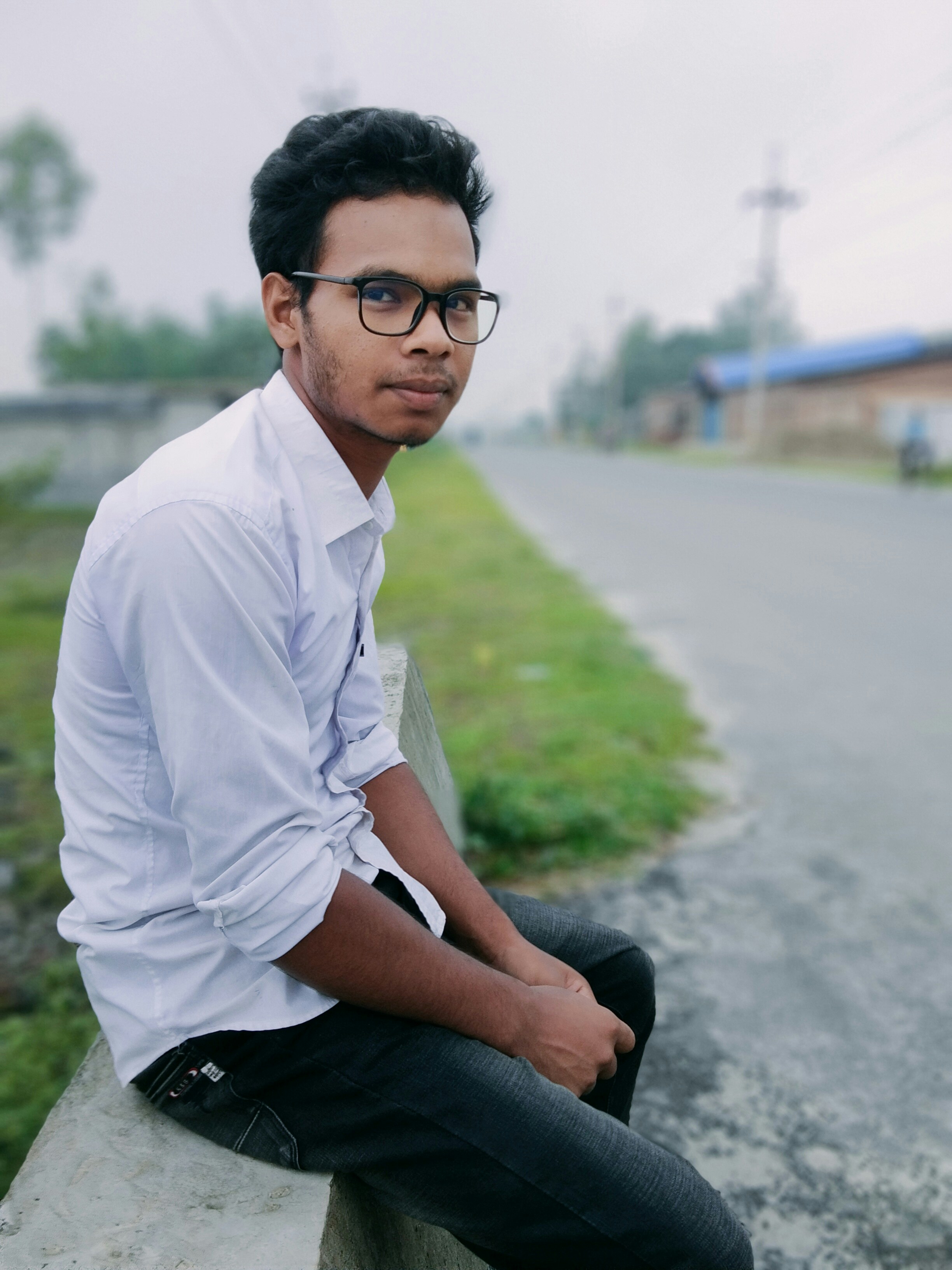 man in white dress shirt and black pants sitting on gray concrete road during daytime