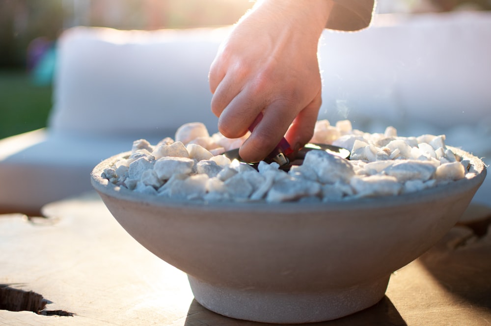 person holding white ceramic bowl with white and blue stones