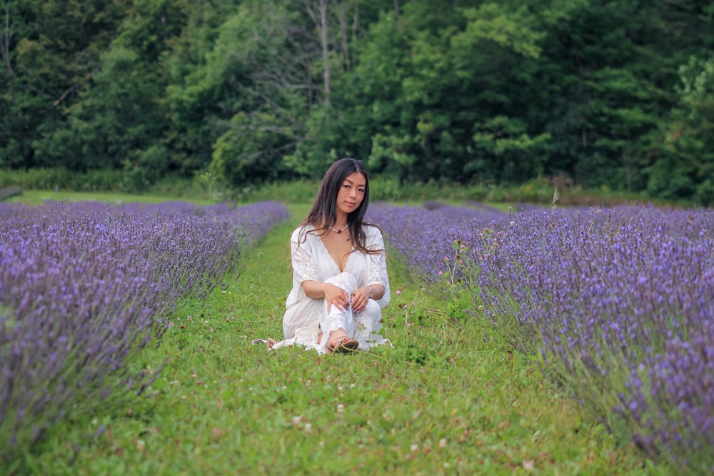 Muchacha en vestido blanco sentada en el campo de hierba verde durante el día