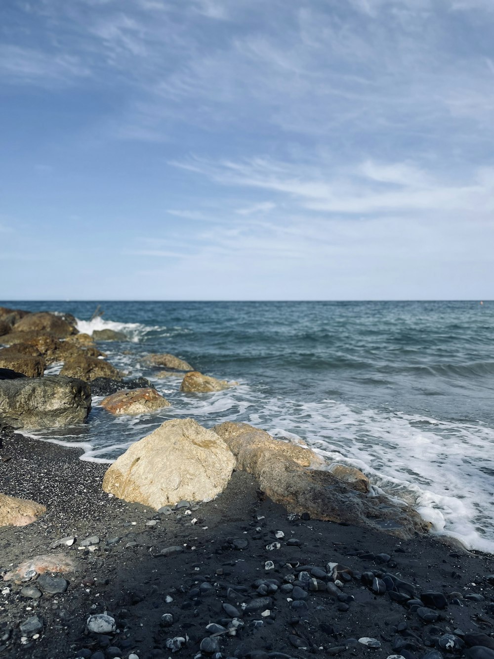 rocas grises en la orilla del mar bajo el cielo azul durante el día