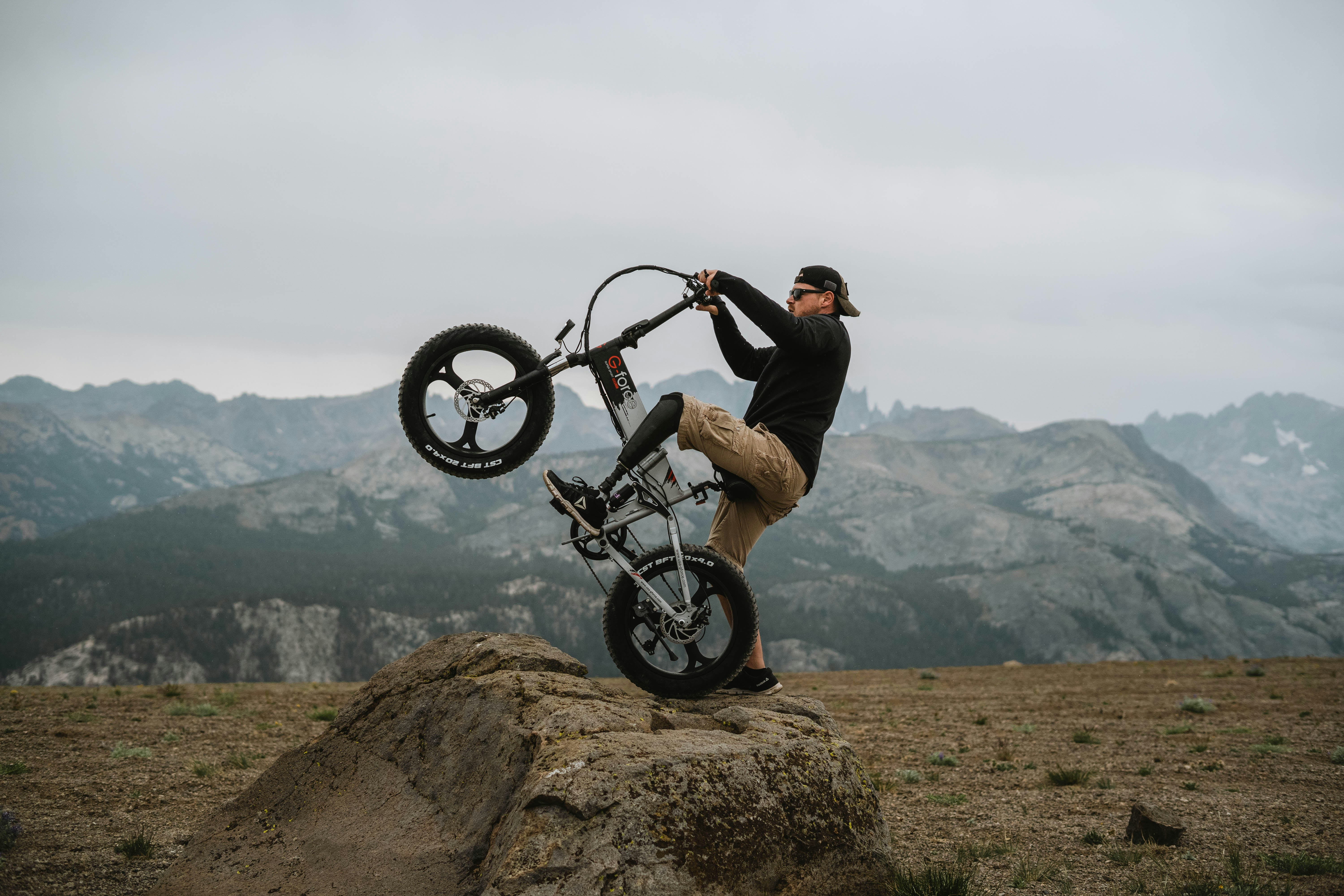 man in black jacket riding black bicycle on brown field during daytime