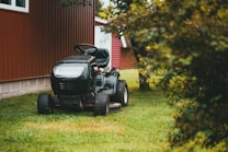 black ride on lawn mower on green grass field during daytime