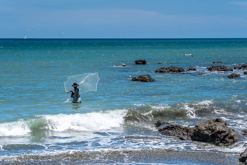 person in black wet suit holding white surfboard on beach during daytime