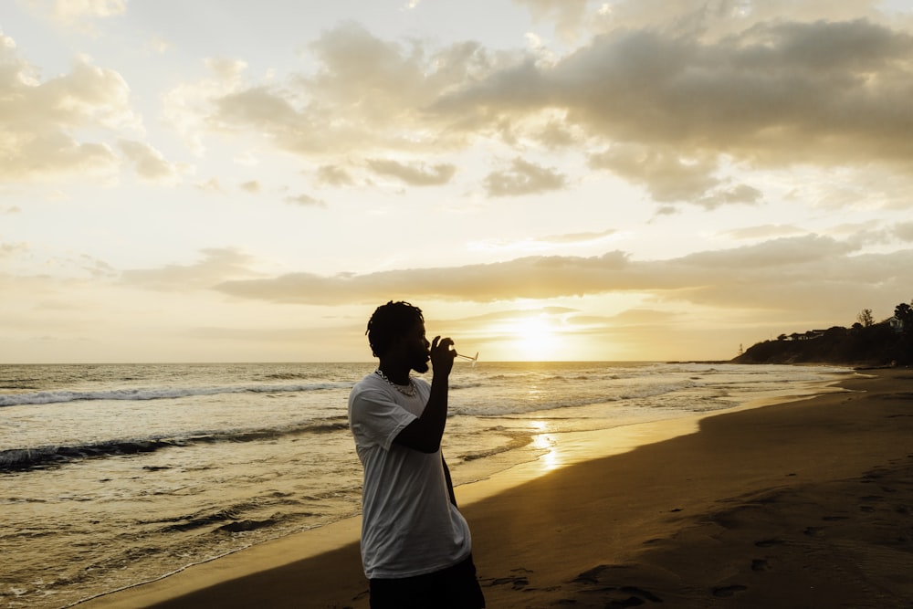 man in white shirt standing on beach during sunset