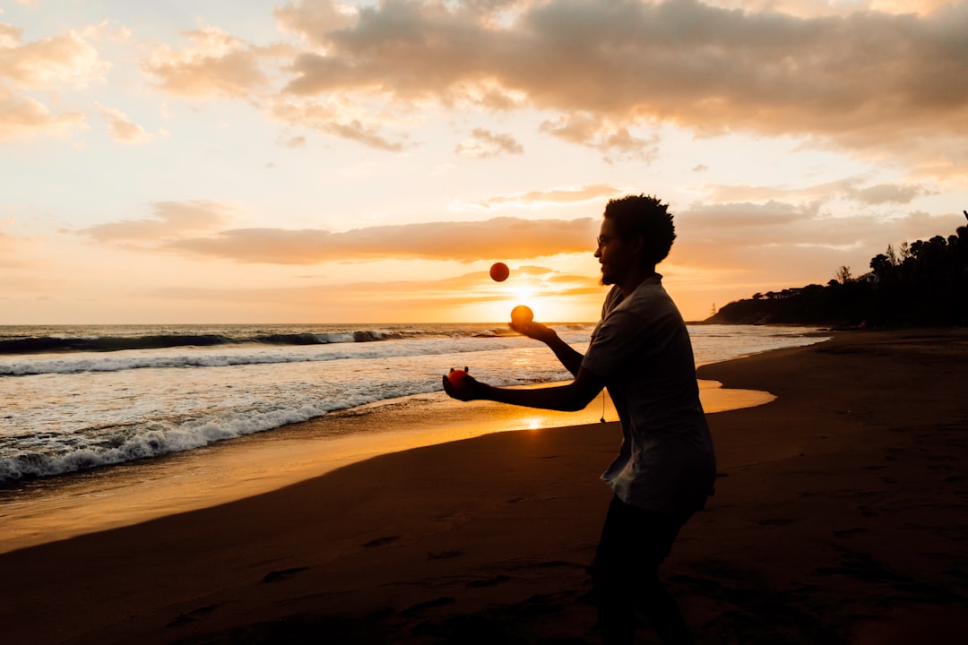 man in white shirt standing on beach during sunset