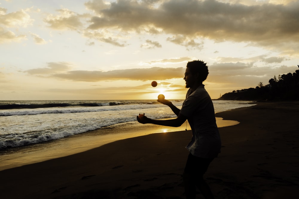 man in white shirt standing on beach during sunset