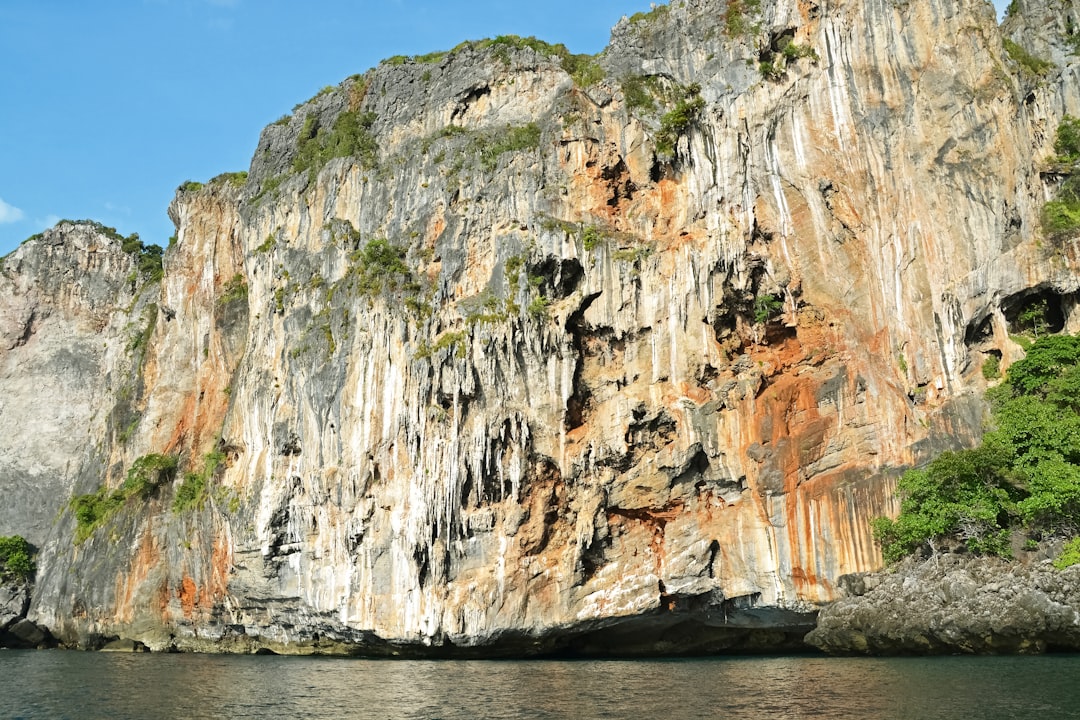 brown and green rock formation on body of water during daytime