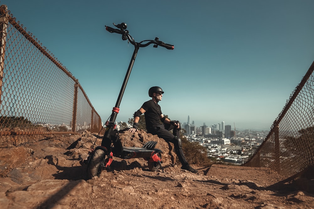 man in black jacket sitting on brown rock during daytime