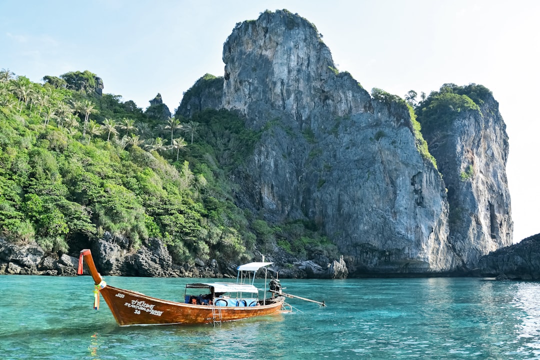 brown boat on body of water near mountain during daytime