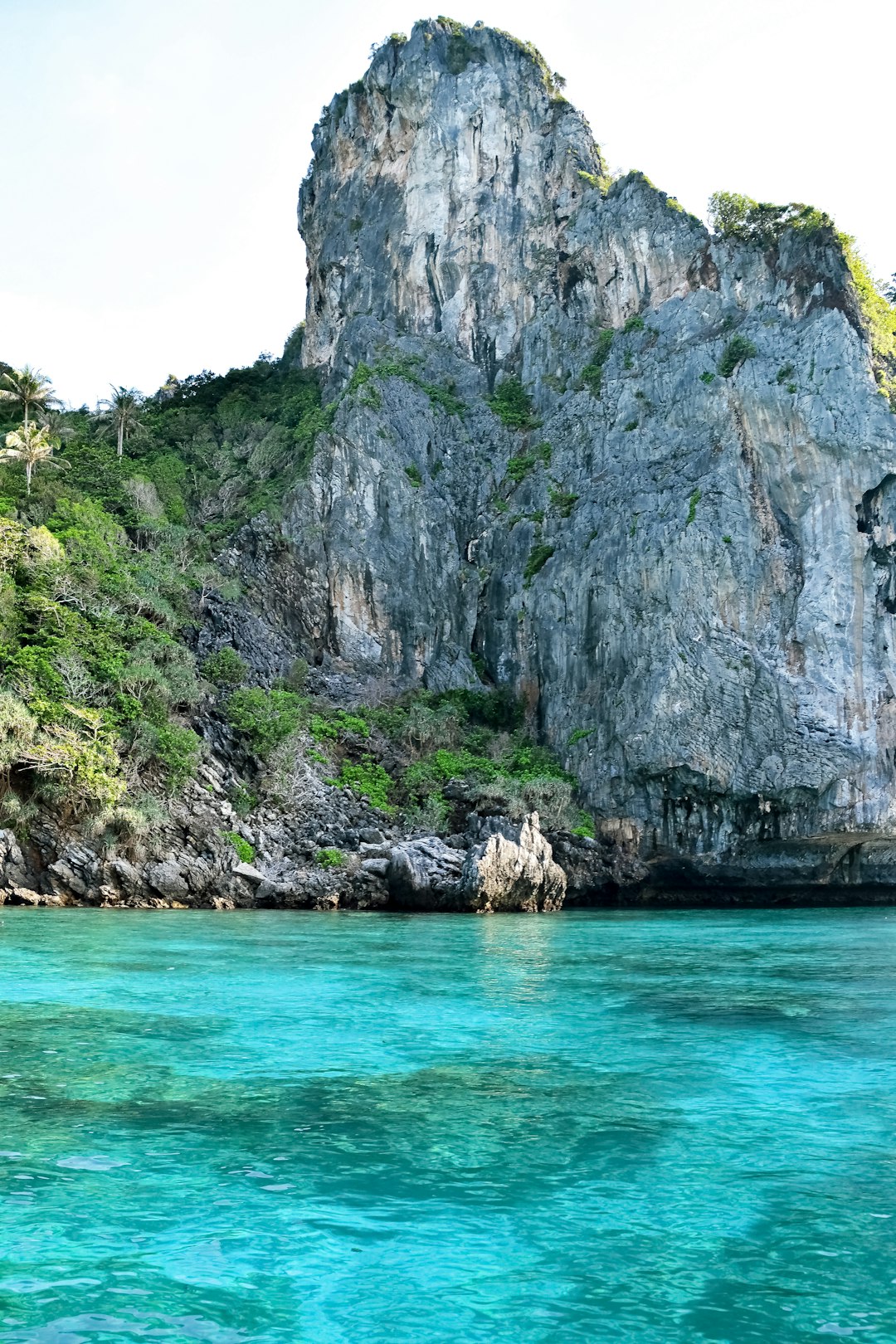 gray rocky mountain beside body of water during daytime