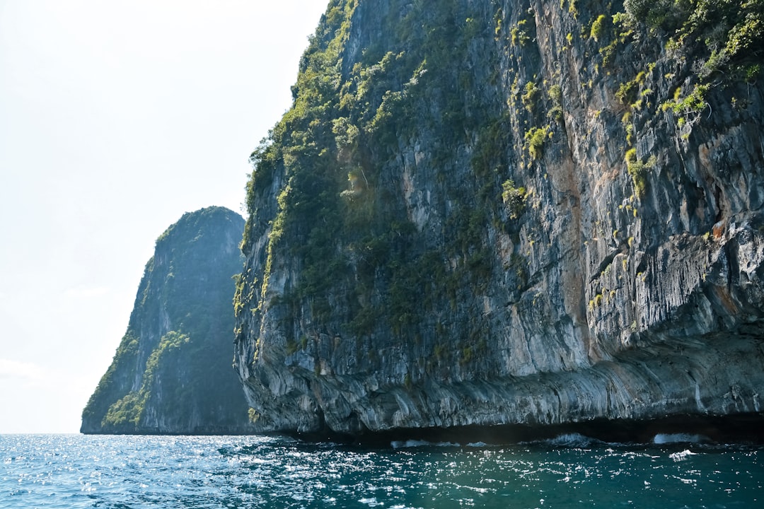 gray and green rock formation beside body of water during daytime