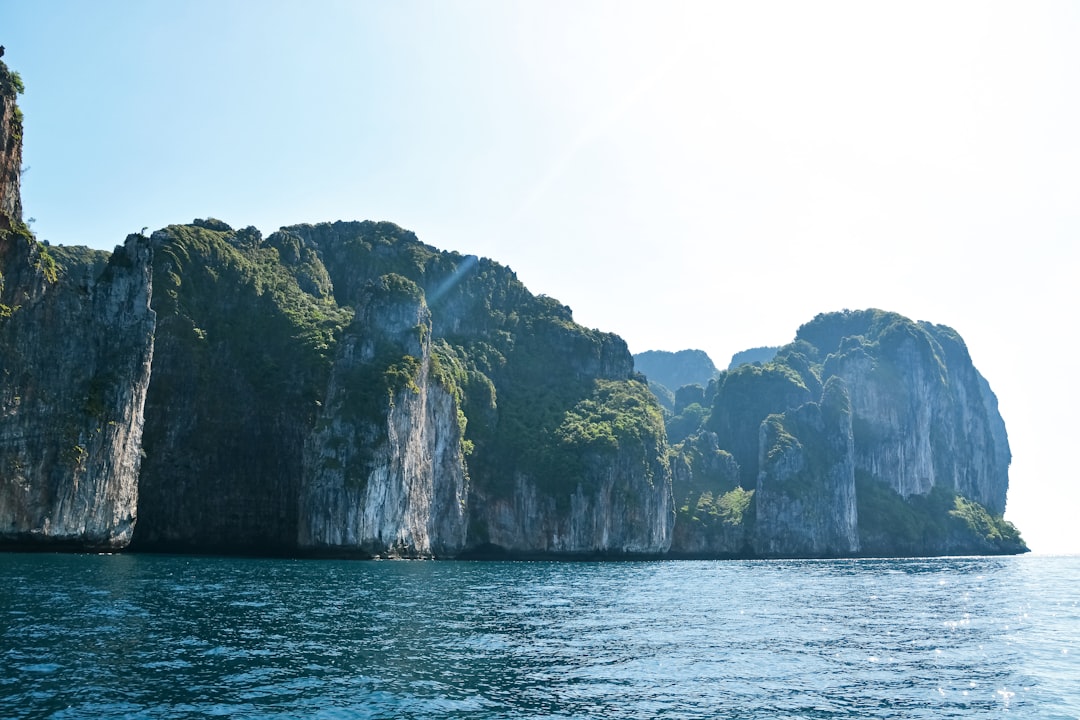 green and brown rock formation on sea during daytime