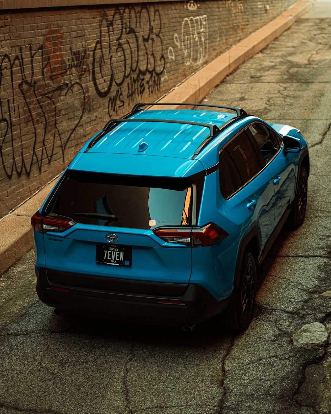 blue honda car parked beside brown brick wall