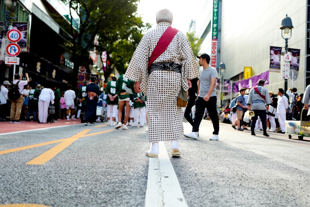 Donna in vestito bianco e nero che cammina sulla strada durante il giorno