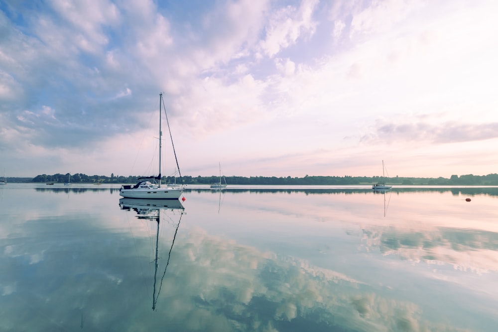 white boat on body of water under cloudy sky during daytime