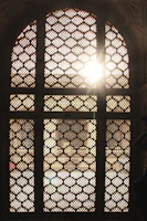 Sunlight filtering through intricate Moroccan latticework onto a cozy riad courtyard.
