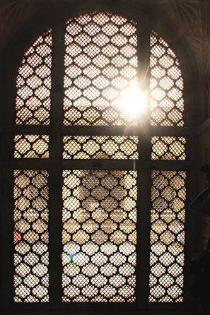 Sunlight filtering through intricate Moroccan latticework onto a cozy riad courtyard.