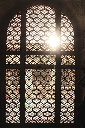 Close-up of colorful cement jali patterns casting intricate shadows.