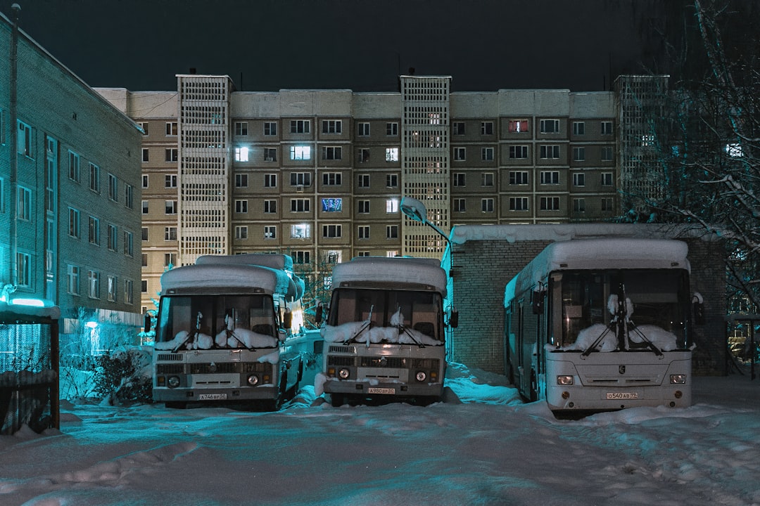 white bus on road near high rise buildings during daytime