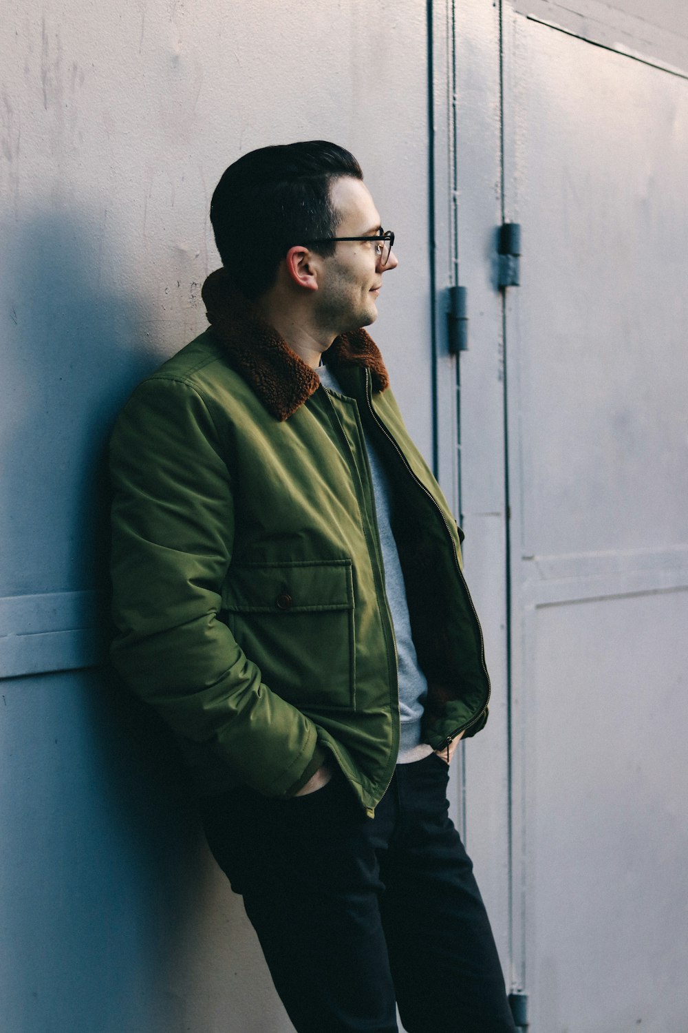 man in green dress shirt standing beside blue wall