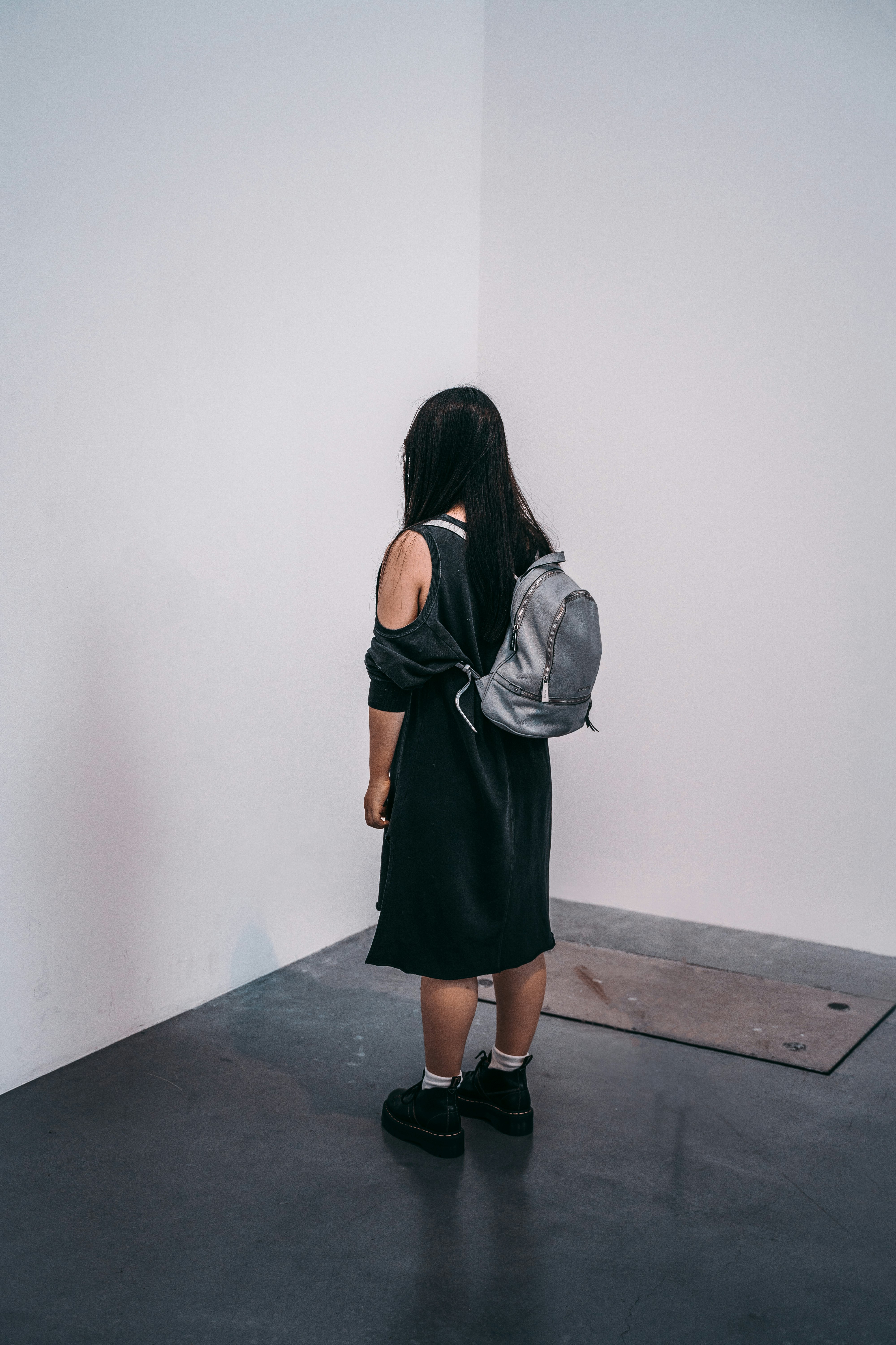 woman in black dress carrying gray backpack