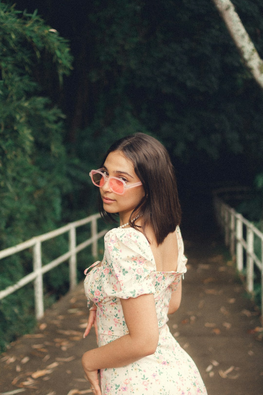 woman in white floral off shoulder dress wearing sunglasses standing on bridge during daytime