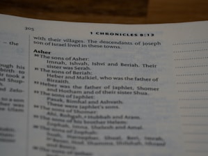 A close-up view of a book page showing text from 1 Chronicles 8:13. The text includes genealogical information about the descendants of Asher, listing names such as Imnah, Ishvah, Ishvi, and Beriah. The font is clear and legible with section headings slightly bolder.