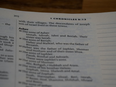 A close-up view of a book page showing text from 1 Chronicles 8:13. The text includes genealogical information about the descendants of Asher, listing names such as Imnah, Ishvah, Ishvi, and Beriah. The font is clear and legible with section headings slightly bolder.