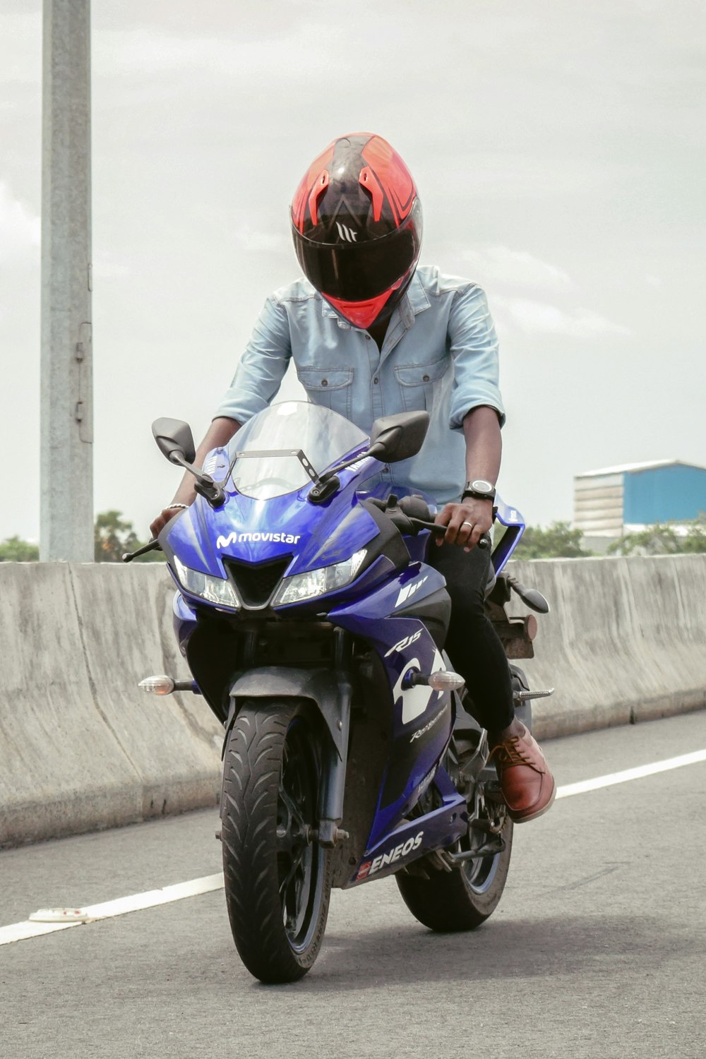 낮 동안 파란색과 검은색 오토바이를 타는 빨간 헬멧을 쓴 남자